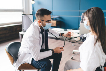 Obraz premium Doctor checking blood pressure with sphygmomanometer and stethoscope