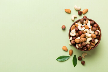 Assortment of nuts in wooden bowl on colored table. Cashew, hazelnuts, walnuts, almonds. Mix of...