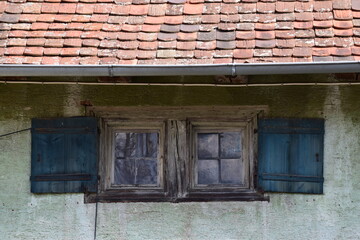 Fototapeta na wymiar Altes Gebäude Bauernhaus, alte Fenster mit Fensterläden und Dach mit roten Dachziegeln 