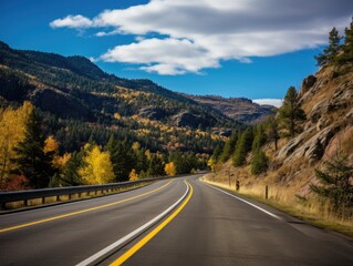 A picturesque mountain drive, surrounded by fall foliage in vibrant shades; the distant horizon gently blurring into autumnal hues.