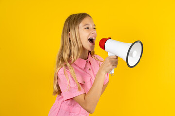 Funny Beautiful caucasian kid girl wearing pink shirt People sincere emotions lifestyle concept. Mock up copy space. Screaming in megaphone.