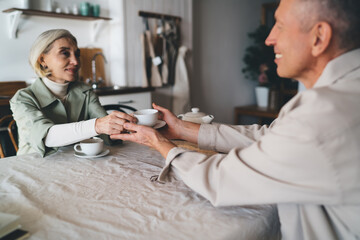 Obraz premium Mature female caring about husband during morning tea at home