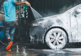Car cleaning. Using water under high pressure to clean a car. Water Covering a Modern Compact Car.