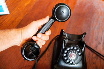 Man holds in his hand the receiver of an old vintage telephone, communication concept.