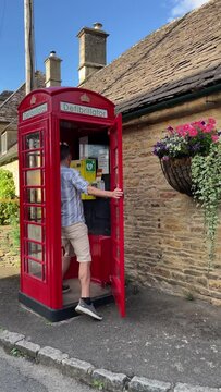 Handsome Caucasian man runs to use a defibrillator installed in an old red telephone booth. 4k vertical 60fps. Concept neighborhood help in an emergency. High quality footage