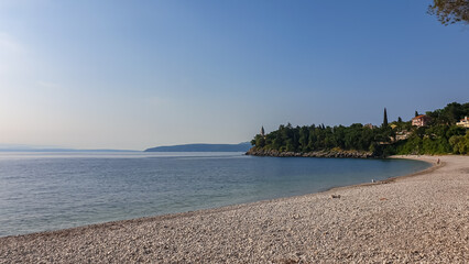 A stony beach along the shore of Medveja in Croatia. The Mediterranean Sea is calm and clear. There...