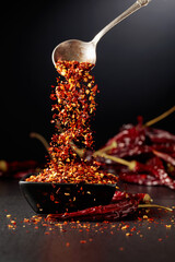 Chilli flakes are poured into a black dish.