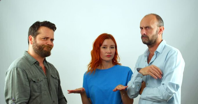 A group of coworkers, a woman and two men, looking at the camera. They are clearly disapproving of something, as they are all shaking their heads and making hand gestures that mean "no"
