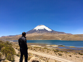Lone man looking at a snowcapped volcano in the Atacama altiplano, Chile.