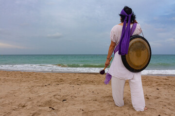 Woman with a meditation gong in the beach