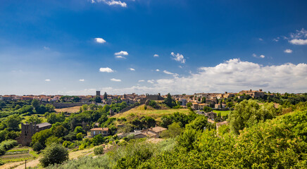 Tuscania, Viterbo, Lazio. A view of the ancient medieval village of Tuscania, city of the Etruscans, from the top of the hill that rises in front of the city. Green countryside, rich in vegetation. - obrazy, fototapety, plakaty