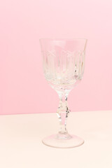 Crystal glass in front of pink background. Minimal composition.