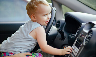 child sitting on mother's knees in the car, cute little boy have fun, lies on cheek on steering...