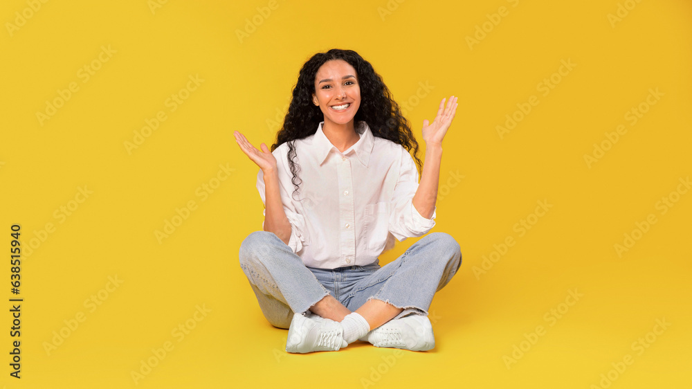 Wall mural Glad Arabic Young Lady Sitting On Floor On Yellow Background