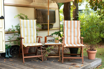 Wooden deckchair and Brown vintage radio near campsite on caravan or camper van. Lounge sunbed in...
