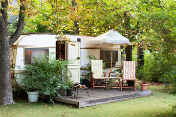 Cozy Campsite on caravan or camper van in forest. Trailer of mobile home stands in garden in...