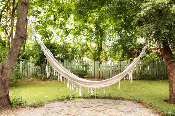 Comfortable Hammock hanging hanging on tree in summer garden. Cozy hygge place for weekend relax in...