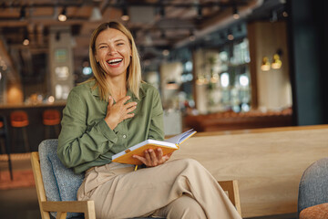 Smiling woman manager sitting on chair in coworking and making notes during working day
