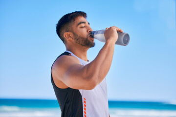 Man, fitness and drinking water on beach in hydration after workout, training or outdoor exercise....