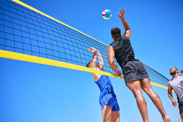 Beach volleyball match, blue sky and sports team jump, playing competition and practice for tournament challenge. Below view, athlete action and people in air workout, training or nature exercise - Powered by Adobe
