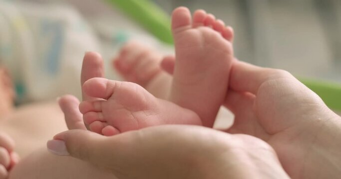 mother holding her lovely newborn baby feet and toes at home, mommy love, happy motherhood.