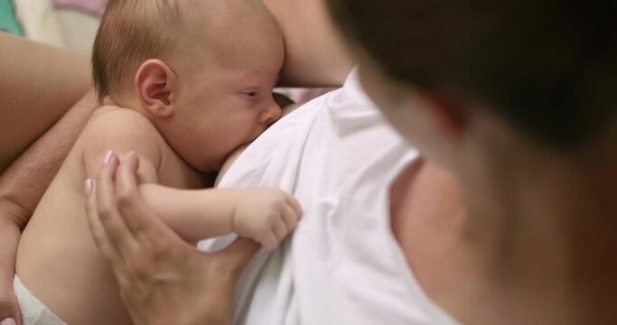 Young mother breastfeeds her newborn baby at home, cozy footage, Caring togetherness motherhood, Innocent, Lactation, mother milk nutrition, real life.