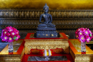 A small figurine depicting a Buddha sitting in a lotus position inside a Thai temple.