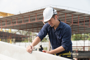 Foreman construction builder inspecting quality of precast concrete wall structure at construction...