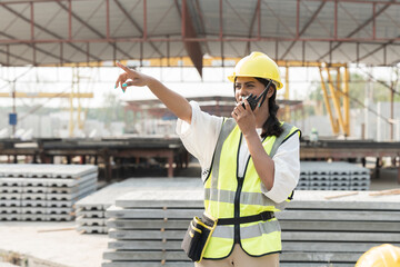 Female construction worker working and discussing with communication radio at construction site....