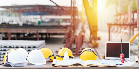 Helmets, blueprint of building, laptop computer on table at construction site. Construction concept
