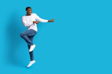Fototapeta premium Excited emotional black guy dancing and pointing at copy space