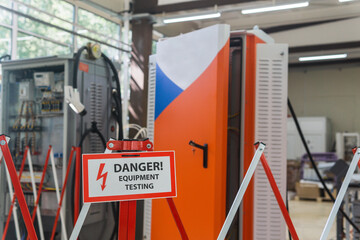 sign with the inscription Danger! Equipment testing! on the fence against the background of blurred...
