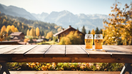 Wooden table top showcase with mug of beer on alpine village background, holiday flags, blank bokeh background