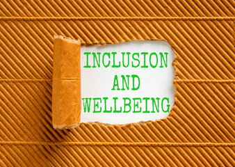 Inclusion and wellbeing symbol. Concept words Inclusion and wellbeing on beautiful white paper. Beautiful brown background. Motivational inclusion and wellbeing concept. Copy space.
