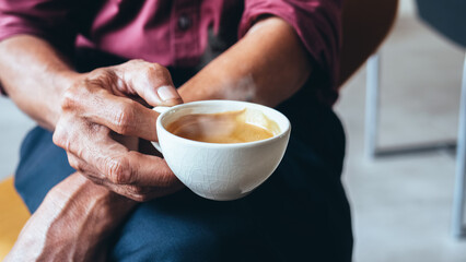 Middle-aged man's hand holding a cup of hot espresso. Business man drinking hot coffee at leisure