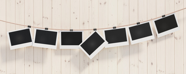 Empty photo frames 16x9 on a light wooden background for your design. Photo frames hang on a rope secured with stationery clothespins. 3D visualization