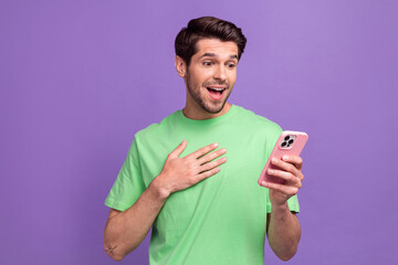 Photo of speechless lucky man astonished staring at smartphone facebook twitter instagram whatsapp isolated on purple color background