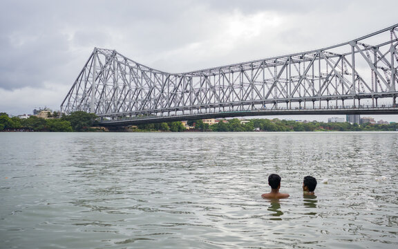 two boys bathing together in the hooghly river water in kolkata. Majestic howrah bridge in the background. photo symbolizes acceptance of homosexuality  or gay relationship or friendship.
