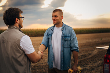 Farmer is having a handshake in the field with his partner.