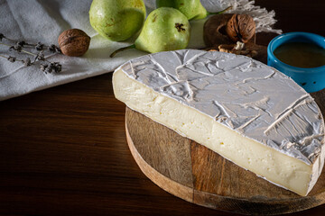 Camembert and brie cheese on wooden background with nuts, honey and fruits. Dairy products.