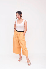 Obraz premium A stoic and intense young Asian woman staring fiercely ahead with hands in pockets. Isolated on a white background.