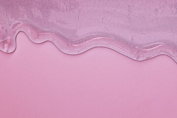 viscous pure transparent cosmetic gel on pink background. tactile , skincare, cosmetics concept. flow soft texture. element for advertising, design