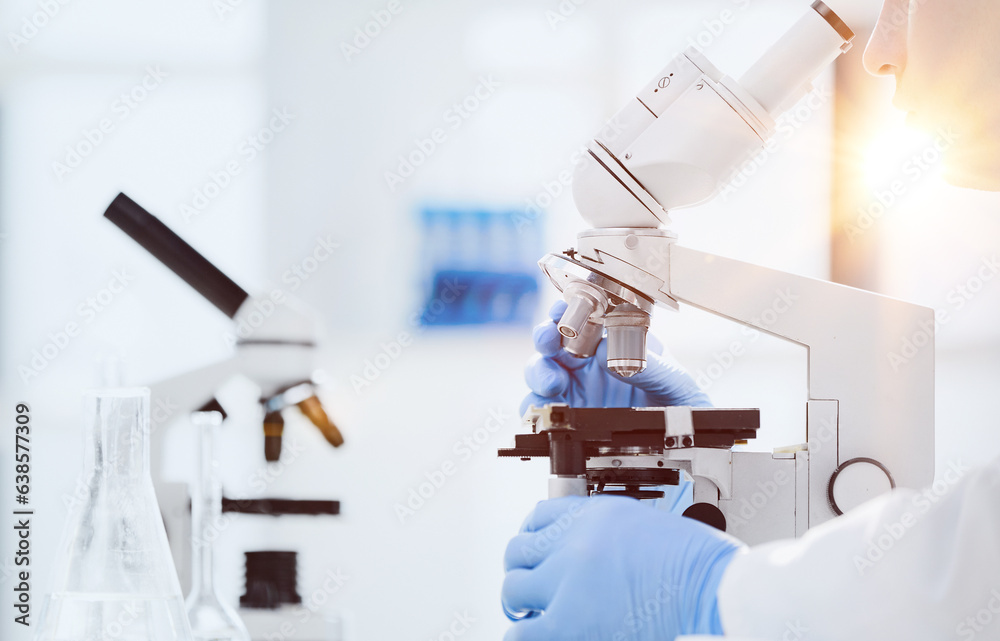 Wall mural scientist looks into a microscope near the laboratory, close-up