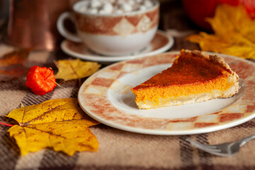 Traditional American Homemade pumpkin pie on a rustic table with cosy autumn decorations and maple leaves