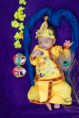 newborn baby boy in krishna dressed with props from unique perspective in different expression