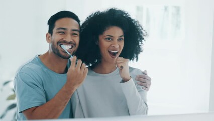 Happy couple, brushing teeth and mirror in morning routine, dental hygiene or care in bathroom at home. Interracial man and woman cleaning mouth, oral or gums in happiness or tooth whitening together