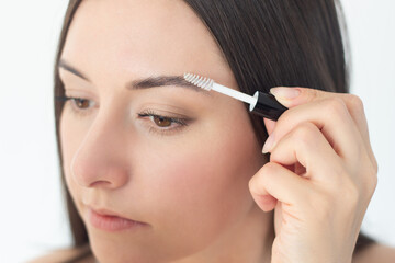 close-up of the face of a young pretty woman who takes care of her eyebrows, doing styling with an eyebrow fixator.