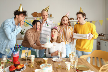 Young woman making wish at birthday party with her friends