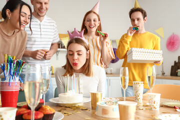 Young woman making wish at birthday party with her friends