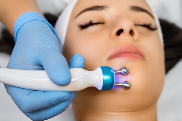 Beautiful woman has a facial microcurrent massage in beauty salon 